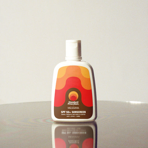 Standard Procedure × Gelato Messina SPF 50 sunscreen bottle scented with mango, pineapple, and vanilla standing on a reflective white surface.
