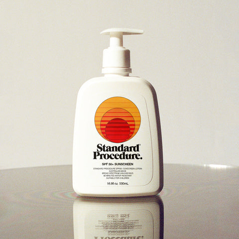 Broad spectrum SPF 50 sunscreen pump bottle with Standard Procedure logo on a reflective white surface.