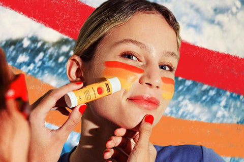 SPF 50 sunscreen stick being applied to a woman's face with vibrant orange and red stripes