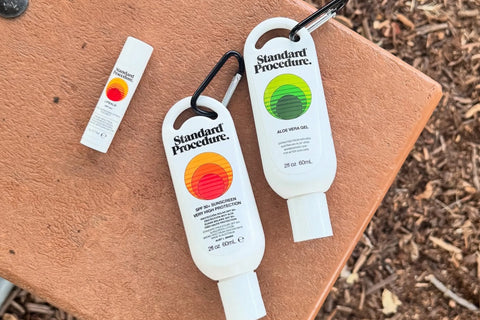 SPF 50 sunscreen and aloe vera gel with carabiners placed on an outdoor bench