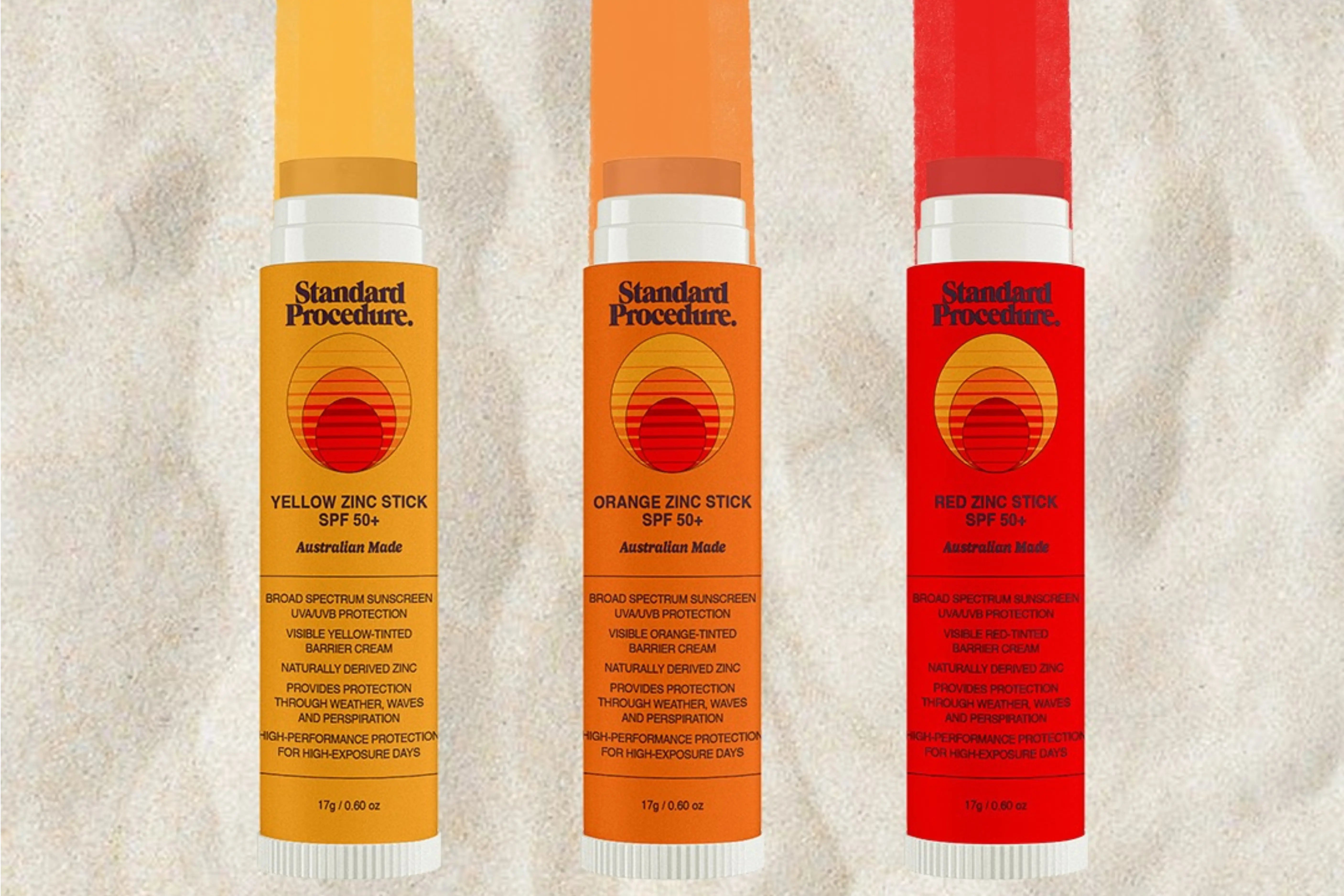 Standard Procedure daily SPF use zinc sticks in yellow orange and red displayed on sand