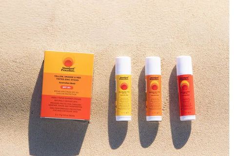 Standard Procedure tinted zinc sticks for daily use of sunscreen laid out on sand