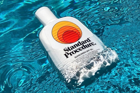 Water-resistant sunscreen bottle floating in a clear blue swimming pool.
