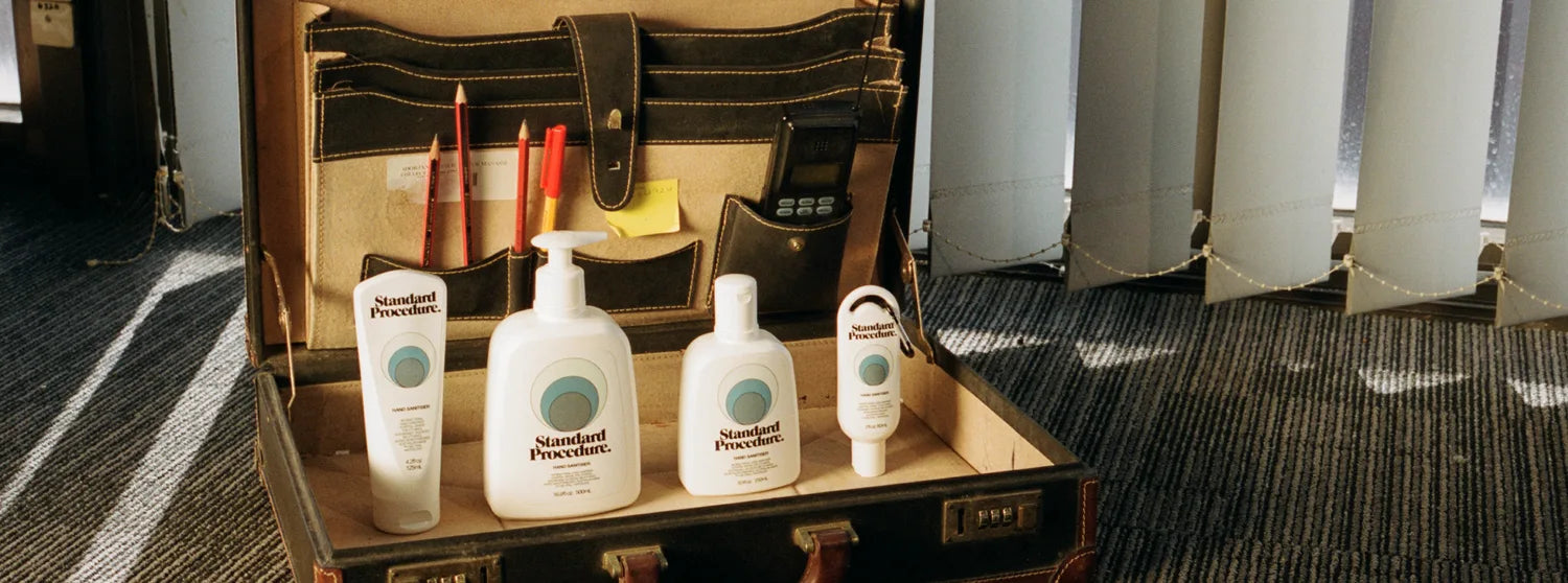 Standard Procedure hand sanitiser bottles in four sizes arranged inside a vintage leather briefcase.