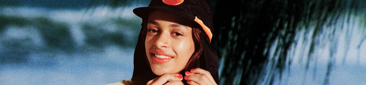 Smiling person wearing Standard Procedure's black sun-protective sport hat with neck flap outdoors.