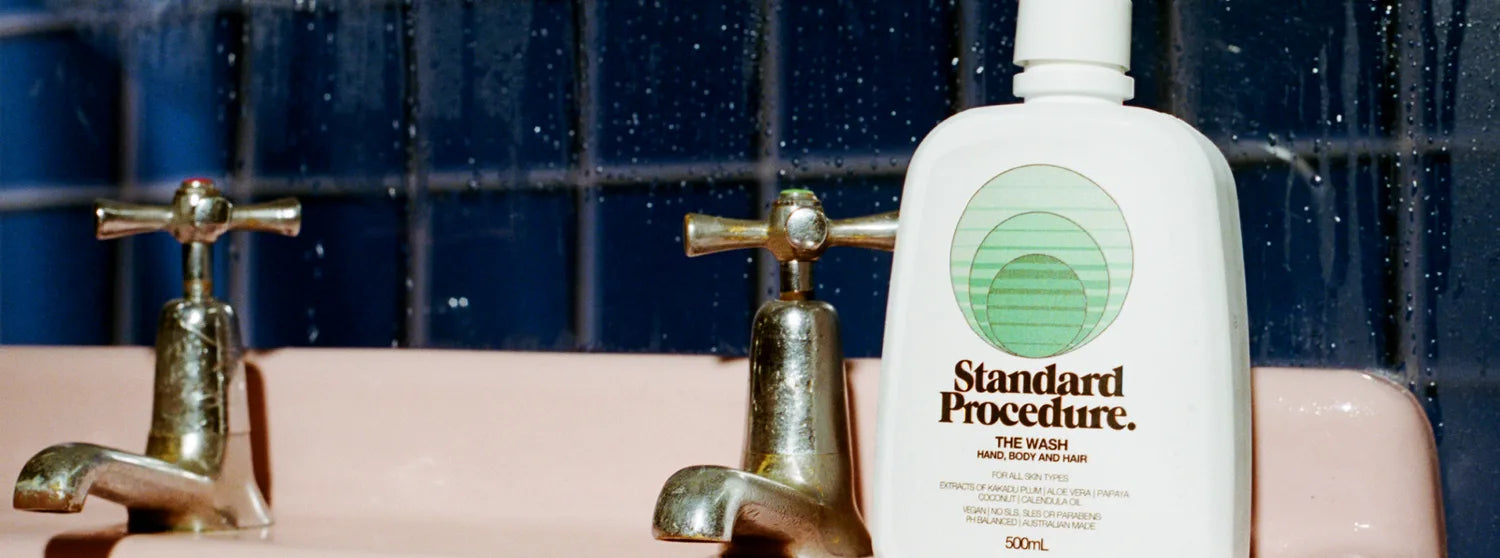 Standard Procedure The Wash 500mL aloe vera body wash on a pink basin beside brass taps.