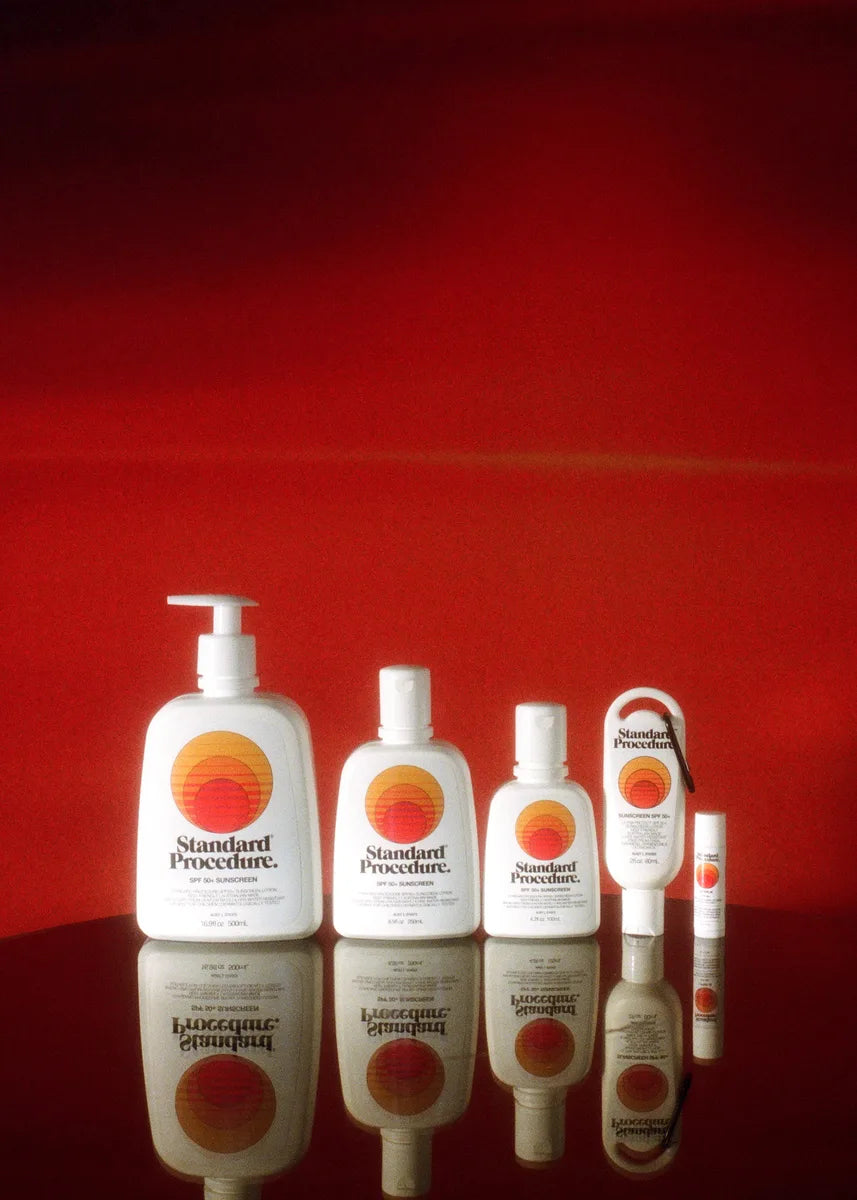 Full Standard Procedure SPF 50+ sunscreen range lined up against a deep red backdrop.