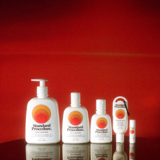 Full Standard Procedure SPF 50+ sunscreen range lined up against a deep red backdrop.