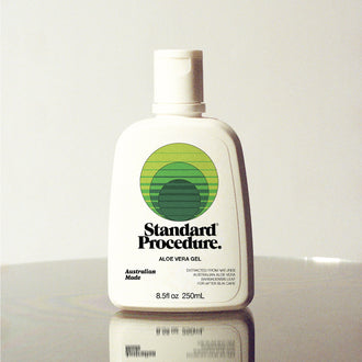 Standard Procedure Aloe Vera Gel 250ml bottle with a flip-top cap on a reflective surface with a grey background.