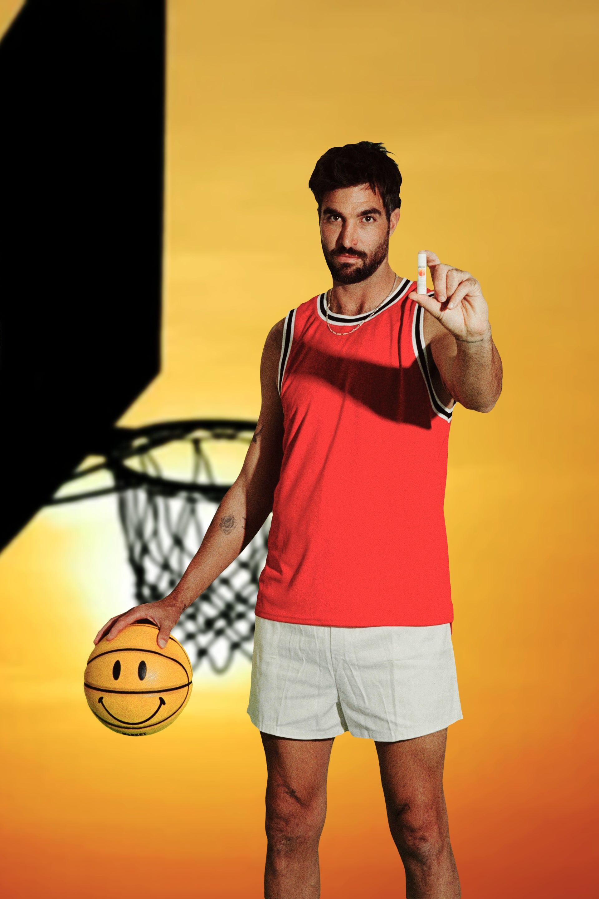 Basketball player in red jersey holds up SPF 50 lip balm beside a sunset-lit hoop.