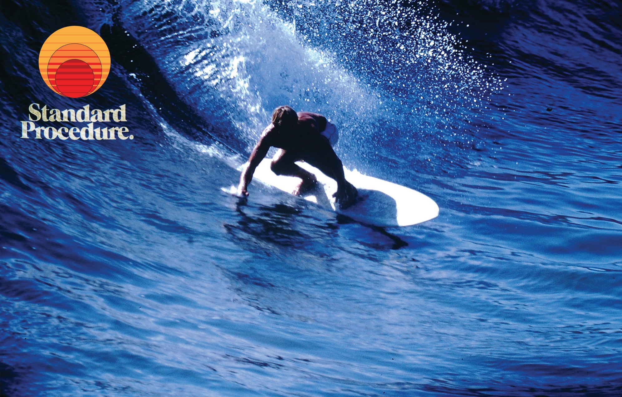 Surfer carving a deep blue wave, branded lifestyle shot for Standard Procedure aloe vera after-sun gel.