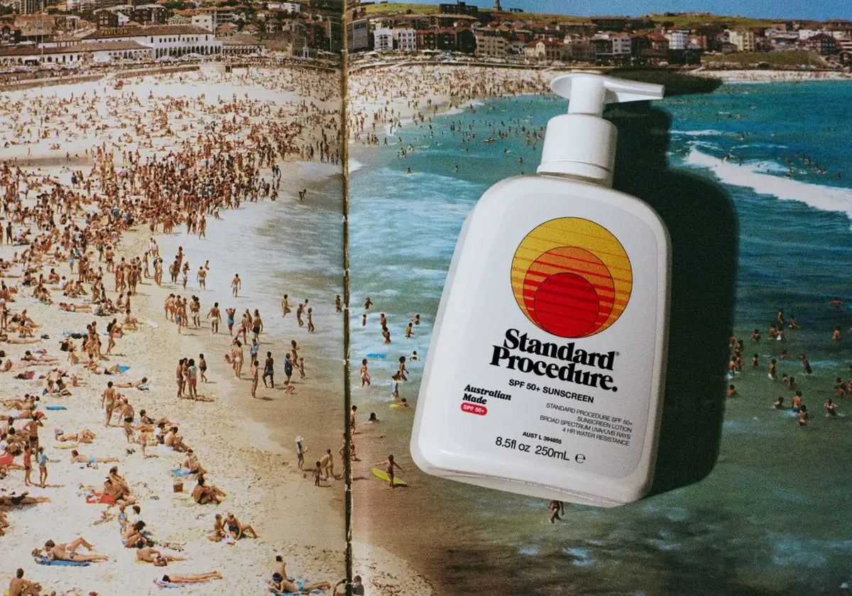 Standard Procedure SPF 50+ sunscreen pump bottle floating above a crowded Australian beach.