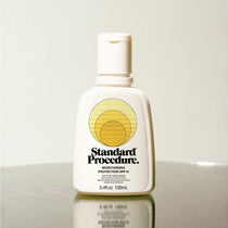 Standard Procedure Moisturising Protection SPF 15 100ml bottle on a reflective surface with a neutral background.