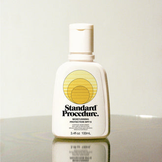 Standard Procedure Moisturising Protection SPF 15 100ml bottle on a reflective surface with a neutral background.