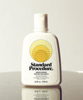 Standard Procedure Moisturising Protection SPF 15 250ml bottle with a flip-top cap on a reflective surface.