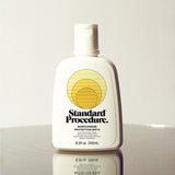Standard Procedure Moisturising Protection SPF 15 250ml bottle with a flip-top cap on a reflective surface.