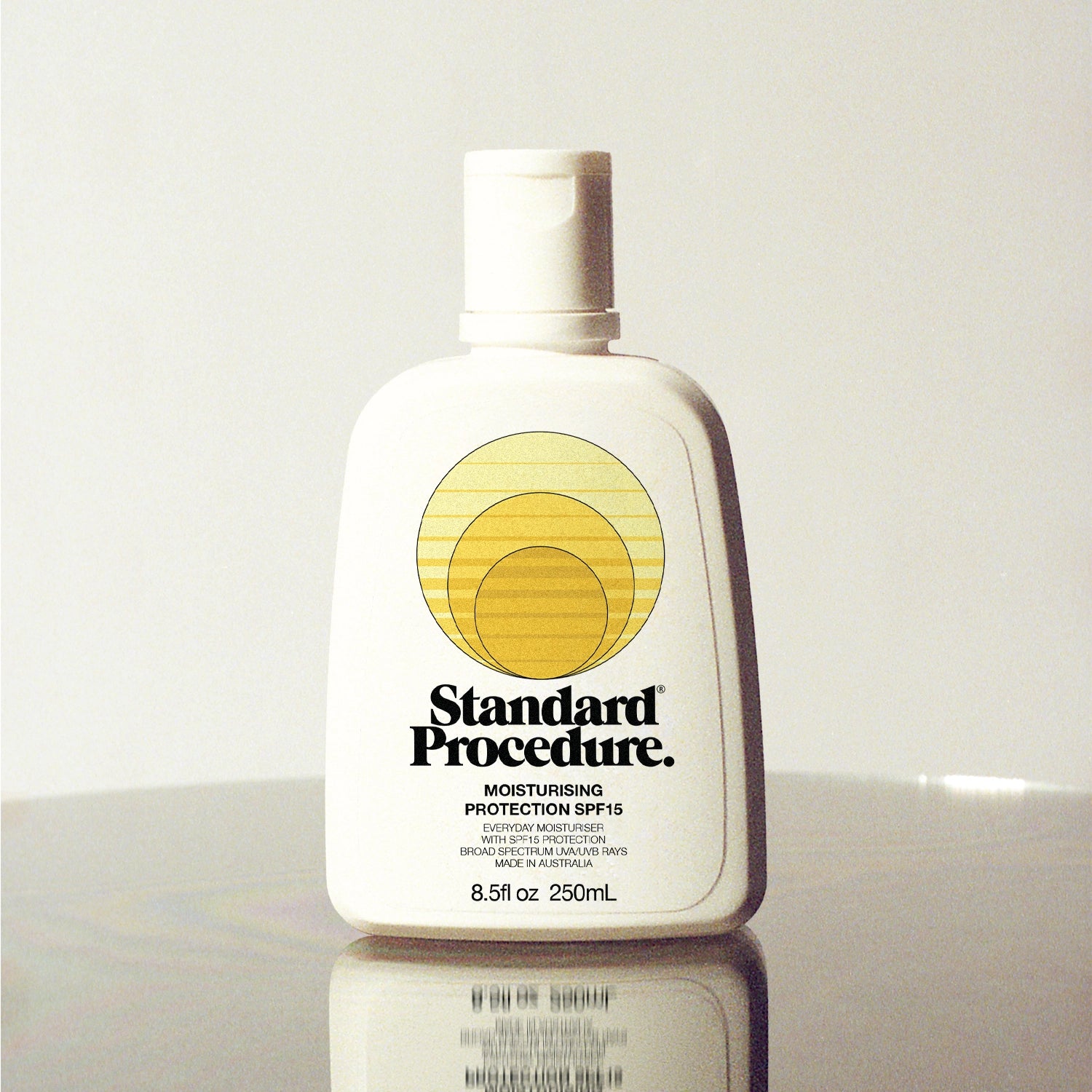 Standard Procedure Moisturising Protection SPF 15 250ml bottle with a flip-top cap on a reflective surface.