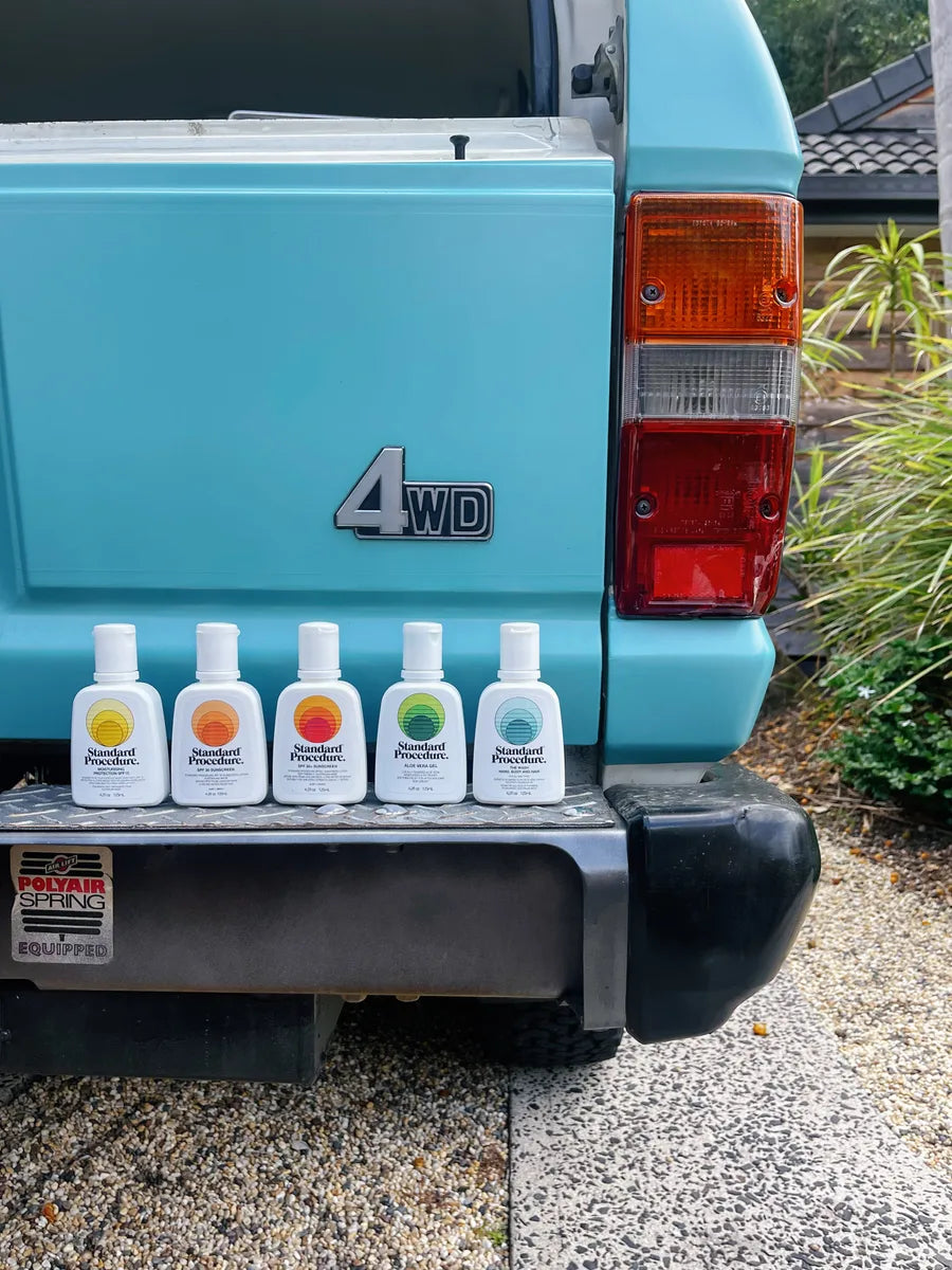 Standard Procedure sunscreen and skincare range lined up on a teal 4WD tailgate.