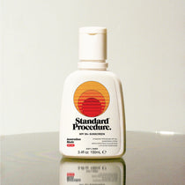 Standard Procedure SPF 50 Sunscreen 100ml bottle with the sunset logo on a reflective surface.