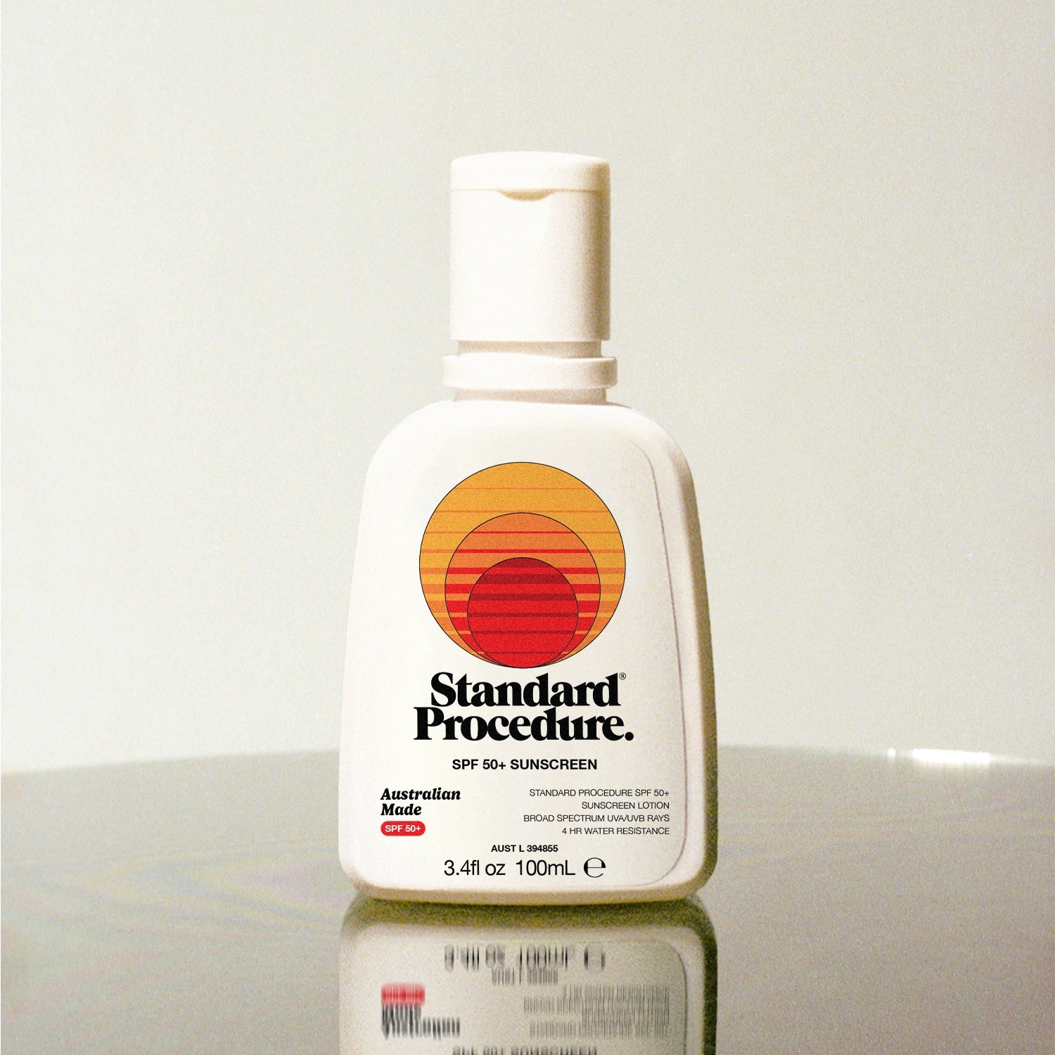Standard Procedure SPF 50 Sunscreen 100ml bottle with the sunset logo on a reflective surface.