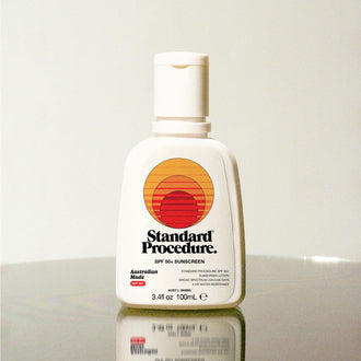 Standard Procedure SPF 50 Sunscreen 100ml bottle with the sunset logo on a reflective surface.