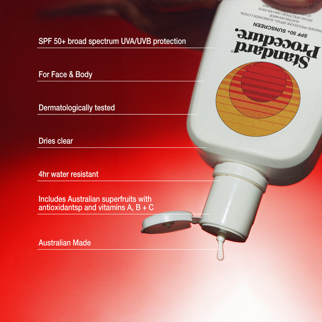 Broad spectrum sunscreen SPF 50 bottle tilted against a red gradient background with its flip-top cap open and a drop of lotion falling.