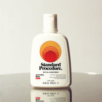 Standard Procedure SPF 50 Sunscreen 250ml bottle with a flip-top cap on a reflective surface.