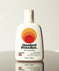 Standard Procedure SPF 50 Sunscreen 250ml bottle with a flip-top cap on a reflective surface with a grey backdrop.