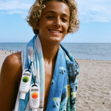 Person on a beach with a towel and sunscreen