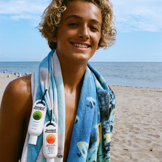Person on a beach with a towel and sunscreen
