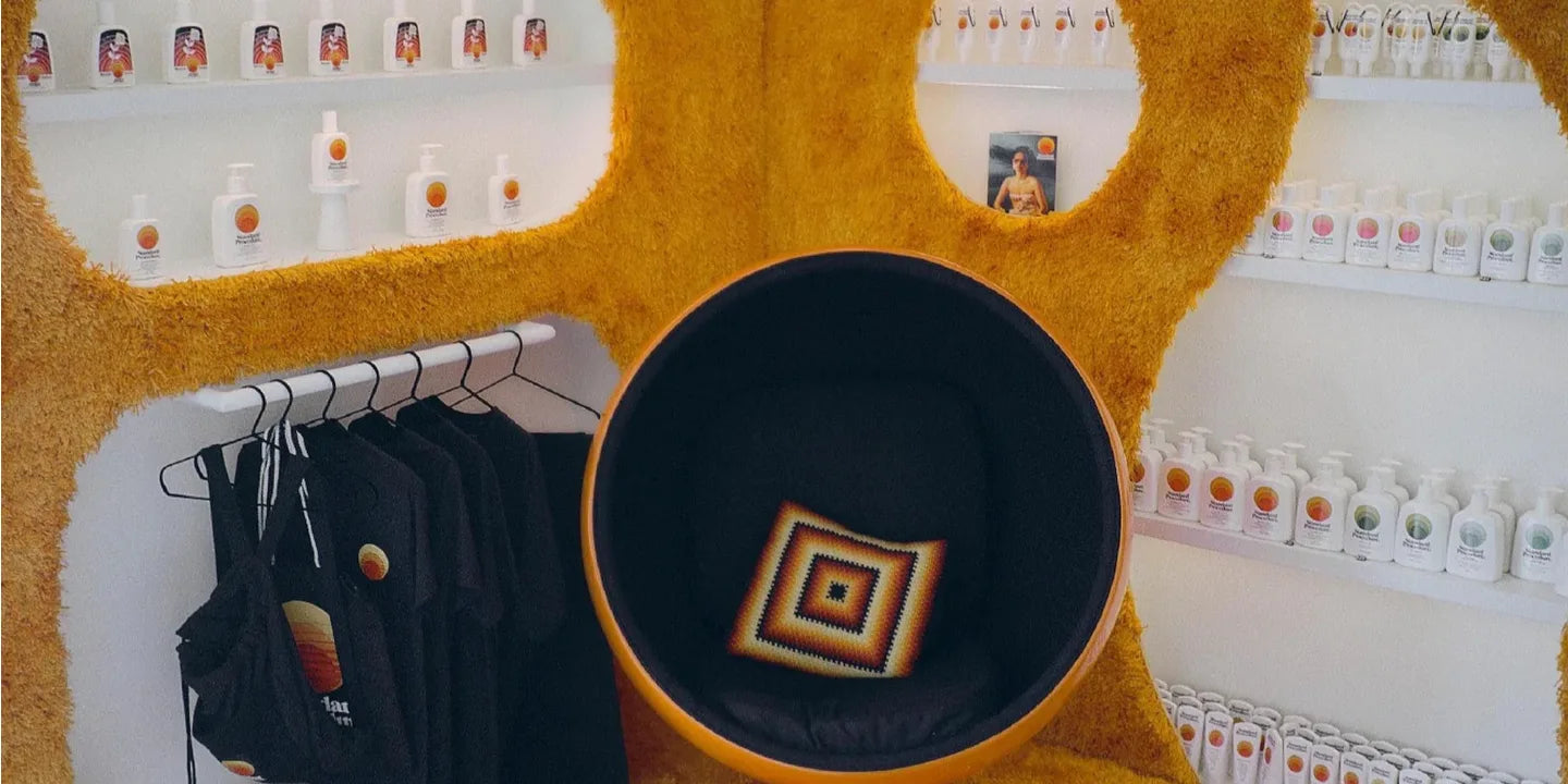 Standard Procedure pop-up store shelves lined with sunscreen bottles, branded tees, and a retro seating pod.