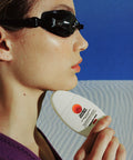 Australian made sunscreen held by a swimmer wearing black goggles and a purple suit, emphasizing UV protection and quality skincare for outdoor activities