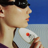 Australian made sunscreen held by a swimmer wearing black goggles and a purple suit, emphasizing UV protection and quality skincare for outdoor activities