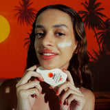 Woman holding a skincare product with a tropical background. Australian Sunscreen with skin benefits