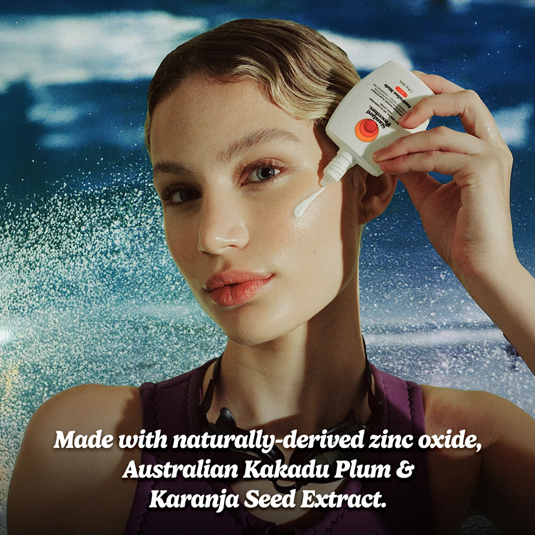 Australian mineral sunscreen applied to a woman’s cheek as she holds the bottle near her face, featuring ocean background and highlighting natural zinc oxide and Kakadu plum ingredients