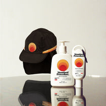 Standard Procedure Sport Hat Pack with a black sunset logo cap, SPF 50 Sunscreen 500ml, and a 60ml travel tube.