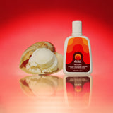 Best sunscreen with vitamin C: SPF 50 Gelato Messina–scented sunscreen bottle beside a scoop of vanilla-pineapple sorbet and a vanilla pod on a reflective surface.