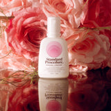 Pleasure Jelly aloe vera lubricant bottle styled against pink roses on a reflective surface.