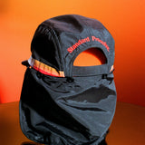 Black surf hat displayed on an orange reflective surface with detachable neck flap and embroidered Standard Procedure logo, designed for durable sun protection and outdoor wear