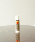 Zinc sunscreen stick standing upright on a reflective surface with minimalist beige background, featuring Standard Procedure label and sun logo design.