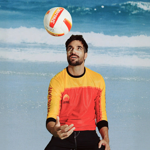 Zinc oxide sunscreen stick under-eye stripe on a beach volleyball player tossing a Spalding ball by the shoreline