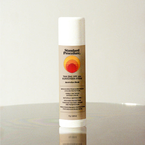 Standard Procedure Tan Zinc SPF 50 Sunscreen Stick 17g with a tinted mineral formula on a reflective surface.