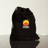 Standard Procedure black drawstring towel bag with an embroidered sunset logo patch on a reflective surface.