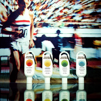 Clip-on aloe vera gel lined up beside sunscreen and sanitiser bottles against a retro tennis backdrop.
