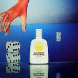 Standard Procedure SPF 15 moisturiser bottle on a mirrored surface beside rolling dice and a sunburnt hand.