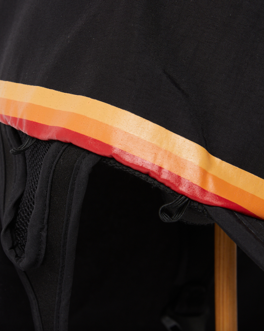 Close-up of black sports hat brim with red and orange retro stripe trim detail.