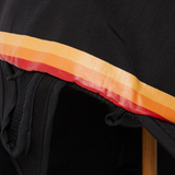 Close-up of black sports hat brim with red and orange retro stripe trim detail.