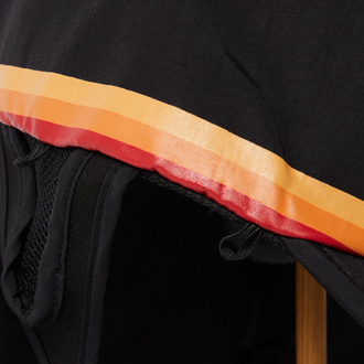 Close-up of black sports hat brim with red and orange retro stripe trim detail.