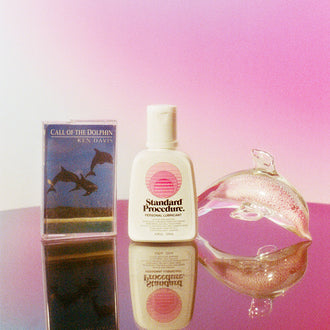 Standard Procedure Pleasure Jelly lubricant bottle beside a glass dolphin and Ken Davis cassette tape.