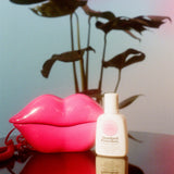 Standard Procedure Pleasure Jelly lubricant bottle beside a pink lips telephone and monstera plant.
